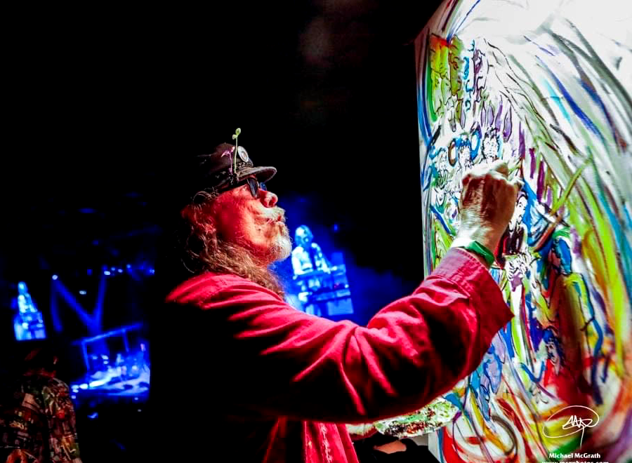 Artist painting colorful mural at live event