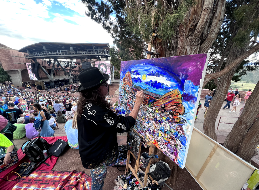 Artist painting colorful canvas at outdoor concert