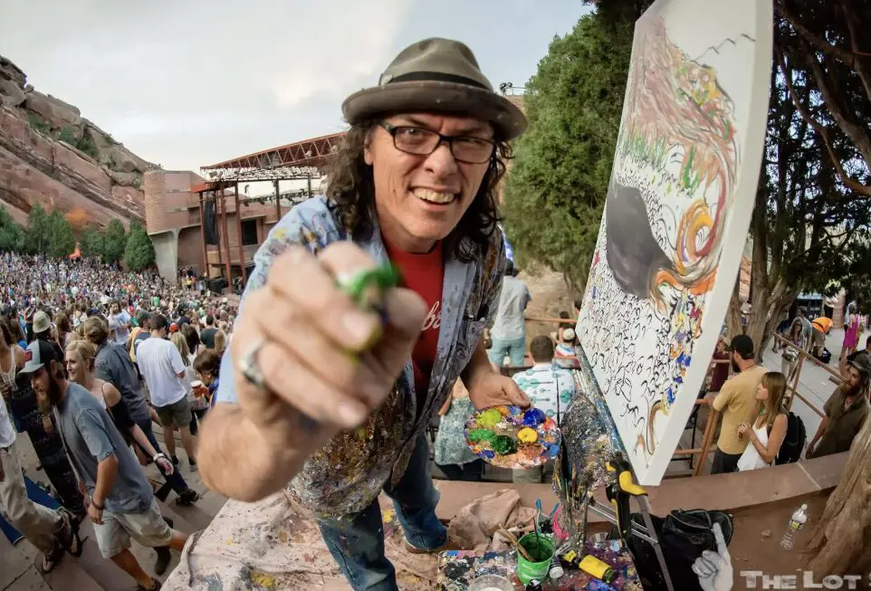 Artist painting on canvas at crowded outdoor concert